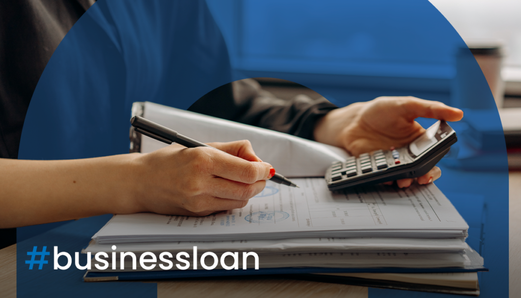 Person working with a book and calculator with the hashtag overlayed saying business loan.