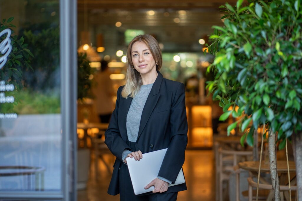 A Bridgement customer and business owner standing outside her growing business with a laptop.