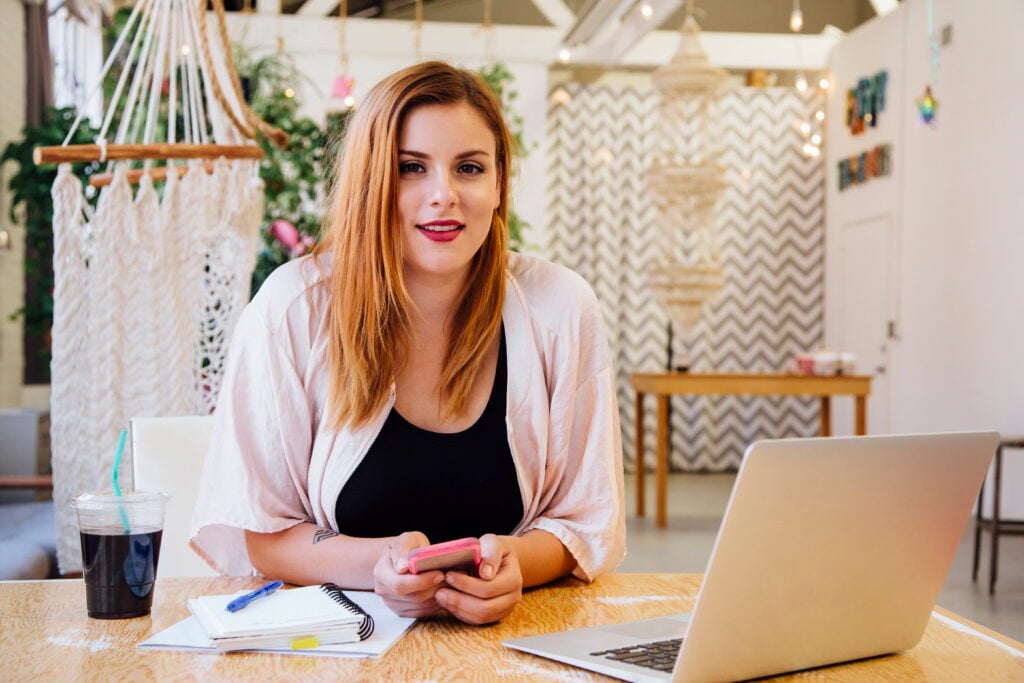 A small business owner planning how to maximise her working capital loan at a café with a laptop and notebook